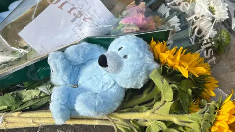 Second arrest in Donaghadee murder inquiry A close up of blue teddy bear, a bunch of sunflowers and floral bouquets with handwritten notes. They are among items placed in tribute to Donaghadee murder victim Sarah Montgomery.