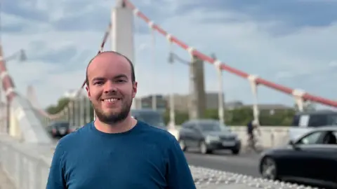 People on £10,000 to £96,000 tell us what they want from the Spending Review Lewis Eager Young man in blue t-shirt standing in front of a suspension road bridge with cars in the background