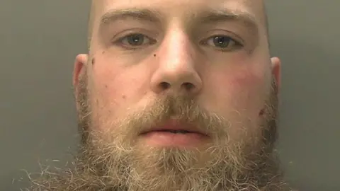Talbot Green police station attacker jailed for attempted murder Counter Terrorism Policing Wales Alexander Dighton is looking straight at the camera in a police custody image.