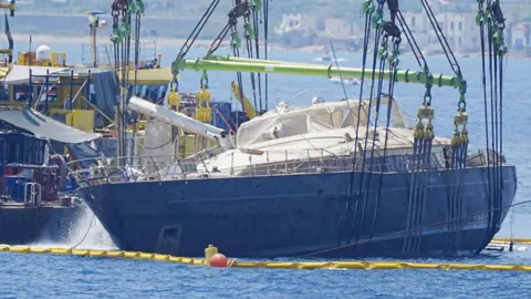 Sunken British superyacht raised from seabed Peter Byrne/PA Wire A ship being held on its side by a crane with water being pumped out of it