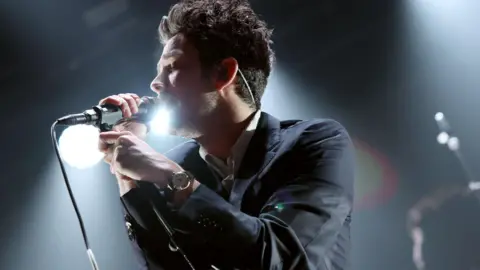 The 1975, Alanis Morissette and more to star on first day of music Getty Images Matty Healy of The 1975 singing into a microphone on stage