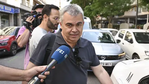 Embattled Sánchez resists clamour for resignation EPA Santos Cerdán is being doorstepped by journalists. He is looking into the camera and a journalist is holding a microphone to his face.