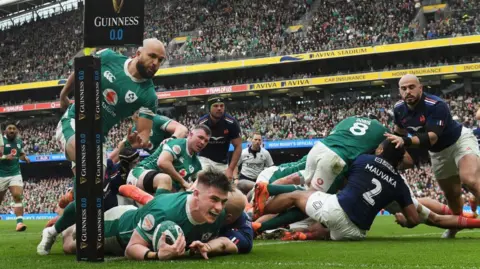 Ticket touts employing workers to bulk-buy for concerts Getty Images Dan Sheehan of Ireland dives over the try line with a ball in his hand to score his team's first try whilst under pressure from Maxime Lucu of France (who is obscured from view) during the 2025 Six Nations Championship match between Ireland and France at the Aviva Stadium in Dublin in March. An Irish teammate of Sheehan is behind him and other players of both sides look on with the stadium view in the background