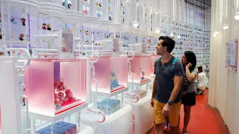 How the Pop Mart dolls conquered the world Getty Images A man and a woman, look amazed, in front of a wall of Pop Mart dolls
