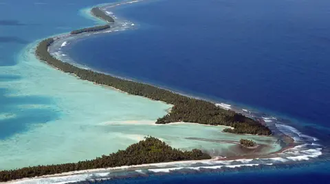 One in three citizens apply for climate change visa Getty Images A very narrow stretch of land is surrounded by shallow turquoise water.