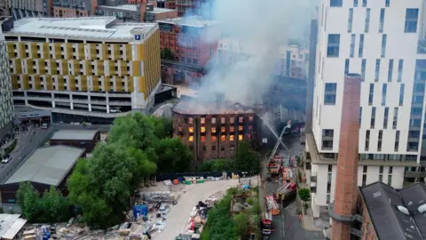 Residents evacuated from tower as blaze spreads JMG Press An aerial view of the Hotspur Press building, with orange flames glowing in the empty windows. The roof of the building has collapsed inwards and smoke is billowing from inside.