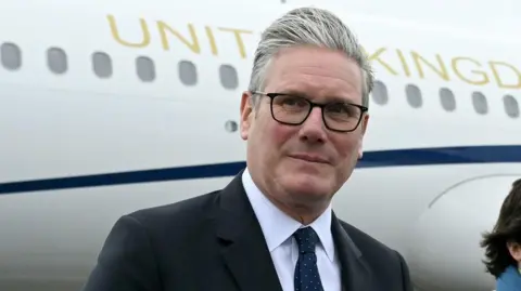 PM vows to press on with welfare cuts despite growing rebellion PA Media Sir Keir Starmer arriving at a NATO summit, walking on airport tarma near a United Kingdom aircraft. A uniformed officer stands beside the stairs leading up to the plane.