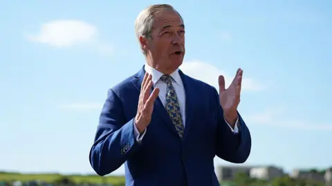 Why Reform was the other big winner in the Hamilton by-election Getty Images Nigel Farage standing outside, wearing a navy blue suit and a yellow and blue tie