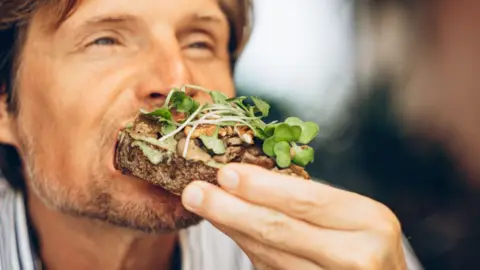 Japanese fruit sando hits high streets Mariia Siurtukova/Getty Images A close-up of a man eating an open sandwich with mushrooms and leaves