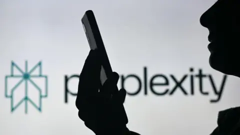 BBC threatens AI firm with legal action over unauthorised content use Getty Images A silhoutted figure is shown holding their smartphone and looking at it in front of a white background displaying the Perplexity logo.