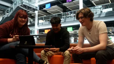 Video games cost a whole day's wages say fans, as prices rise BBC News Kady, Dirk and Nicholas sit on orange sofas playing a multiplayer game together on Nintendo Switch. They're laughing and smiling during a tense race.