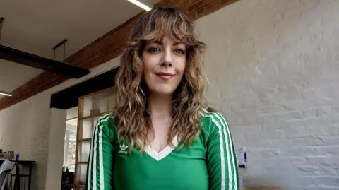 'It was sold as a dream but became a nightmare' Kathy, who is has long curly brown hair with a fringe, wearing a green V-neck Adidas top