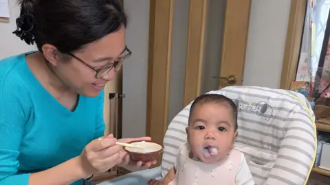 How a joke about rice cost a Japan cabinet minister his job Memori Higuchi Memori Higuchi feeding her 7-month-old baby.