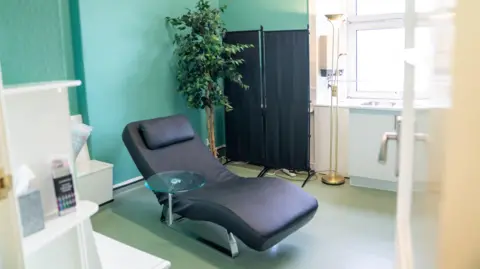 Hopes to open NHS ketamine clinic for treatment resistant depression A photo of the inside of the Eulas clinic. It shows a consulting room. At the centre is a leather reclining chair. It is a sparsely furnished room with a green wall and a potted plant.
