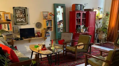 Trump's order to leave Tehran adds to fear as Iranians share 'last photo of home' Social media An image of a colourful living room. Three lounge chairs, a sofa, and various coffee tables are pictured. There is a framed piece of art work with the words 'Let's stay home' above the television.