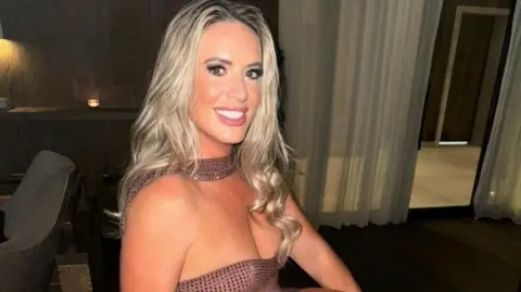Asos customers banned over returns say it is 'slap in the face' BBC A blonde woman in a dress smiles at the camera in front of chairs, tables and curtains in a dimly lit room.