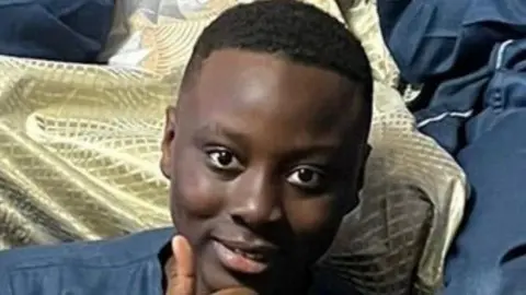 Boys appear in court after 14-year-old stab death Family handout A smiling teenager sits and gives a thumbs up to the camera.
