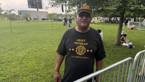 Mass protests against Trump across US as president holds huge military parade Melvin Graves wears a T shirt saying 'Army veteran - still serving America'