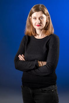 Germany’s young Jewish and Muslim writers are speaking for themselves – exploring immigrant identity beyond stereotypes A blonde woman in a black sweater and dark jeans stands in front of a vibrant blue backdrop.