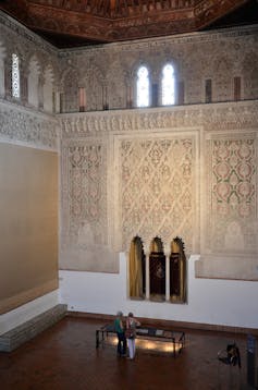 Jews were barred from Spain’s New World colonies − but that didn’t stop Jewish and converso writers from describing the Americas Two people stand in a tall hall with intricately carved windows and designs.