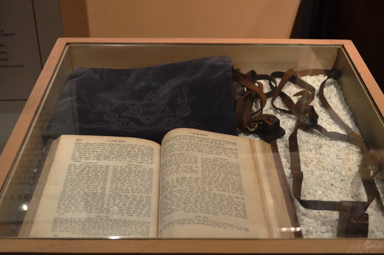 Jews were barred from Spain’s New World colonies − but that didn’t stop Jewish and converso writers from describing the Americas A display case shows an open book with Hebrew text, as well as leather religious objects and a velvet bag.