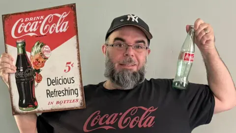 The big winner from Coca-Cola's Trump-inspired sugar push Richard Trappasse Richard Trappasse wears a Coca-Cola T-shirt and New York Yankees hat while holding a glass Coca-Cola bottle and a vintage Coca-Cola advertisement