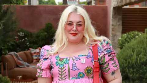 What Guess's AI model in Vogue means for beauty standards Getty Images Blonde woman wearing pink sunglasses and a pink dress