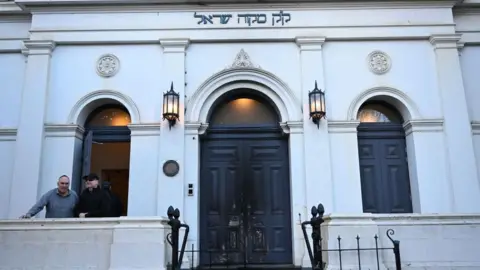 Australian PM vows 'full force of law' after arson attack at Melbourne synagogue JAMES ROSS/EPA/Shutterstock Fire marks on the blue door of the East Melbourne Hebrew Congregation in Melbourne, with two men to the left in front of an open window