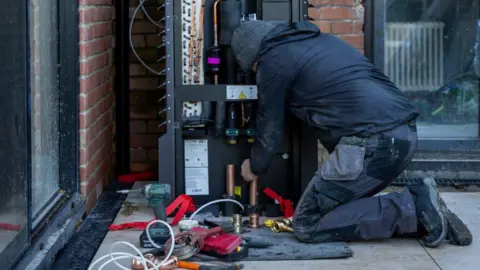 Manufacturers ready for more demand Getty Images A man kneels while installing a heat pump