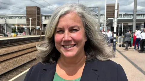 c2c trains are nationalised and return to public ownership Ben Schofield/BBC Heidi Alexander wearing a black blazer over a green T-shirt. She is smiling while standing on a train platform.