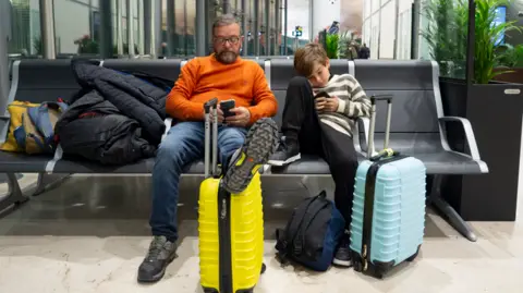 How to save money on planes and accommodation Getty Images Father and son at airport