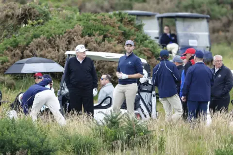 Security tightens as Donald Trump plays golf at Turnberry EPA A number of people, mostly men, on a golf course with a number of golf buggies. President Donald Trump and his son Eric are in the centre of the shot