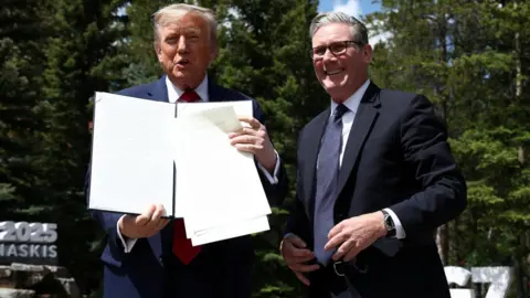 What are tariffs, how do they work and why is Trump using them? Reuters US President Donald Trump holds up a printed copy of the UK-US tariffs deal at the G7 summit in Canada. He stands next to UK Prime Minister Sir Keir Starmer who is smiling