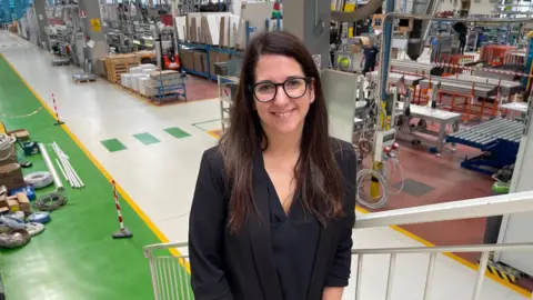 'The village will die' - Italy looks for answers to decline in number of babies Melania, a woman with long dark hair and glasses, is seen in front of a factory floor