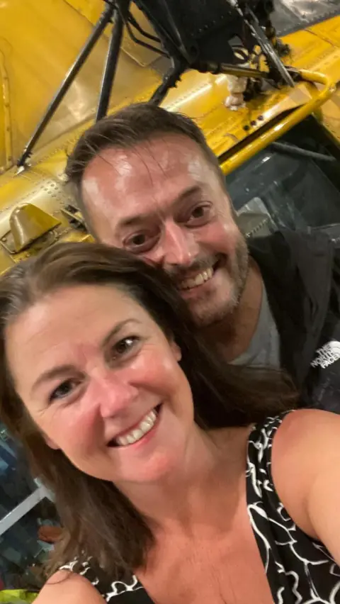 Military aircrew pursuing MoD after cancer diagnoses reaches 180 Anna-Louise Stubbings A selfie of Anna-Louise says Zach who are standing in front of a Sea King helicopter. Anne is wearing a sleeveless black and white dress and has long dark hair. Zach is in dark overalls.