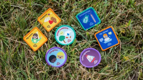 Girlguiding unveils 72 new badges including 'fandoms' and 'laughter' Girlguiding Eight of the new badges laid out on the grass. They are: my voice, kindness, laughter, great outdoors, entomology, clam spaces and my views.