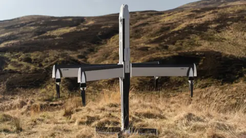 Drone manufacturer STARK to begin production in Swindon STARK A four-winged drone plane, sitting at the bottom of a grassy hill. It is white and black and standing upright