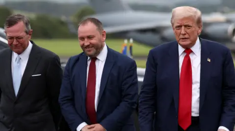 Security tightens as Donald Trump plays golf at Turnberry PA Media Three men from left to right - Warren Stephens, US Ambassador to the UK, Scottish Secretary Ian Murray and US President Donald Trump. They are at an airport with what is likely Air Force One blurry in the background. All three are wearing suits.