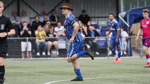 Pete Doherty plays in non-league football friendly for Margate FC Margate FC Pete Doherty running on a football pitch. He is wearing a blue kit and a brown hat.