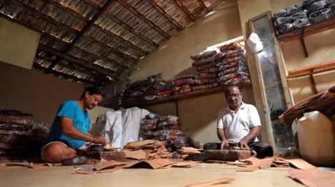 Why Indian footwear artisans are upset with the luxury Italian label Two artisans make leather sandals at their workshop in Kolhapur, Maharashtra