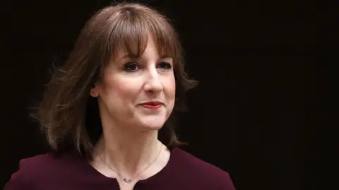 EPA Chancellor Rachel Reeves wearing a dark purple top and pictured against a black background