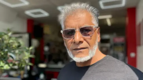 How did no-one know about mum and daughter's death for months? Jamil Ellahi in a grey t-shirt and sunglasses with a white beared