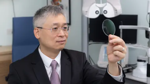 'Autofocus' specs promise sharp vision, near or far Hong Kong Polytechnic University Prof Chi-Ho To holding up a lens.