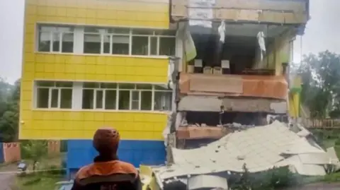 Tsunami alerts scaled back after huge earthquake prompts evacuations across Pacific Russian Emergencies Ministry via EPA A rescue worker wearing a red hard hat stands in front of a damaged building that is two storeys tall and the front of it looks like it has been ripped away