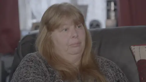 Imported dogs 'posing risk to UK', RSPCA warns A woman with long, reddish blonde hair is sitting on a grey sofa, wearing a grey knitted jumper and is looking to her left, as she is in conversation with our BBC reporter off-camera