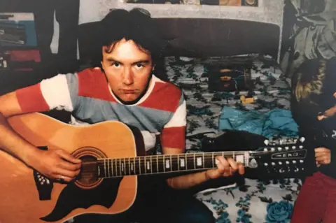 Trainspotting author Irvine Welsh says AI has made us dumbed down machines Irvine Welsh Irvine Welsh looking to camera in red, white & check T shirt playing the guitar