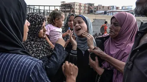 Dozens killed by Israeli gunfire near aid distribution sites, Hamas-run ministry says Getty Images A group of women comfort another woman in the middle of their group in Khan Yunis.
