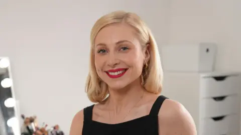 Latin makeup labels put allergy sufferers at risk, say campaigners BBC Amy, who has shoulder length blonde hair and wears a sleeveless black top, smiles at the camera. Behind her is a mirror and a number of makeup brushes
