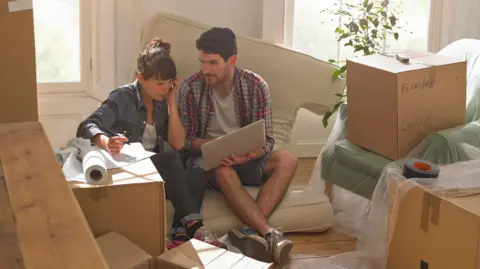 Rents rise by £221 a month in three years, Zoopla analysis suggests Getty Images A man and a woman sit on a cushion looking at a laptop computer surrounded by unpacked boxes.