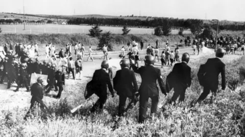 Battle of Orgreave national inquiry confirmed by Yvette Cooper PA Media A black and white image of miners and police officers with riot gear walking along a field.
